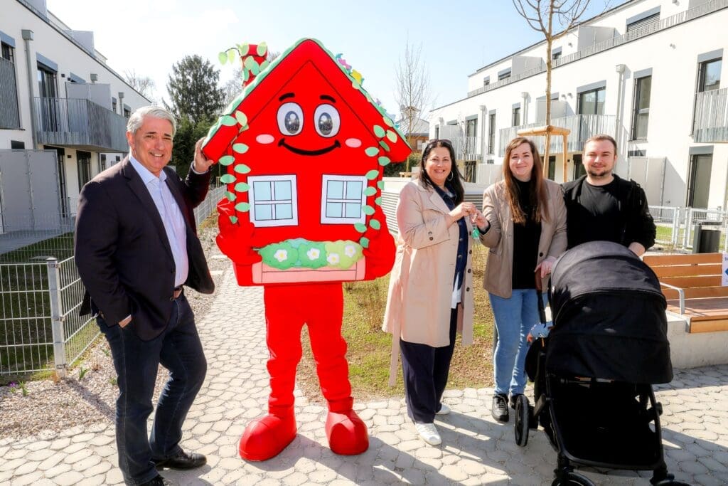 Maskottchen, neue Bewohner und Vizebürgermeisterin bei der Übergabe der Wohnungen von Gemeindebau Neu