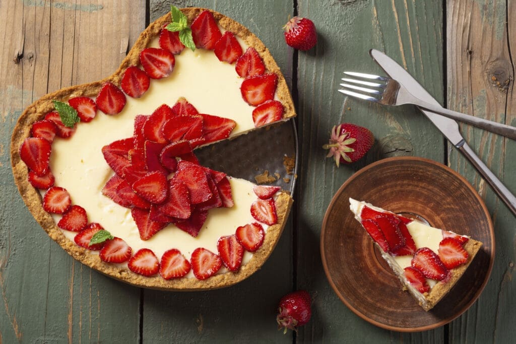 Torte in Herzform mit Vanille und Besteck auf Holz