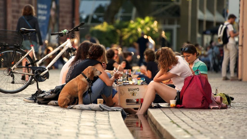 Frauen sitzen an einem städtischen Rinnsal und picknicken