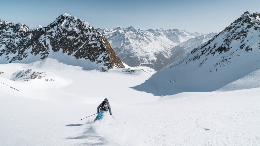 Freerider im Schnee vor imposanten sonnenbeschienenen Berggipfeln